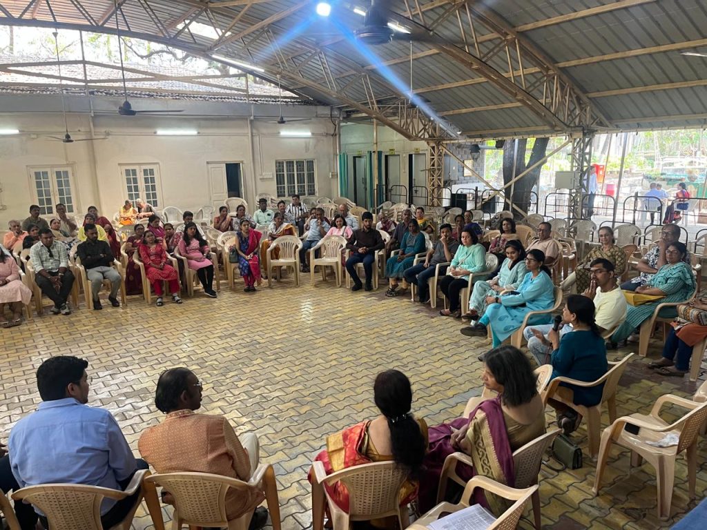 Attendees seated in a circle in a covered hall