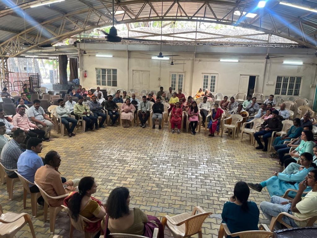 A wide view of attendees seated in a circle in the hall